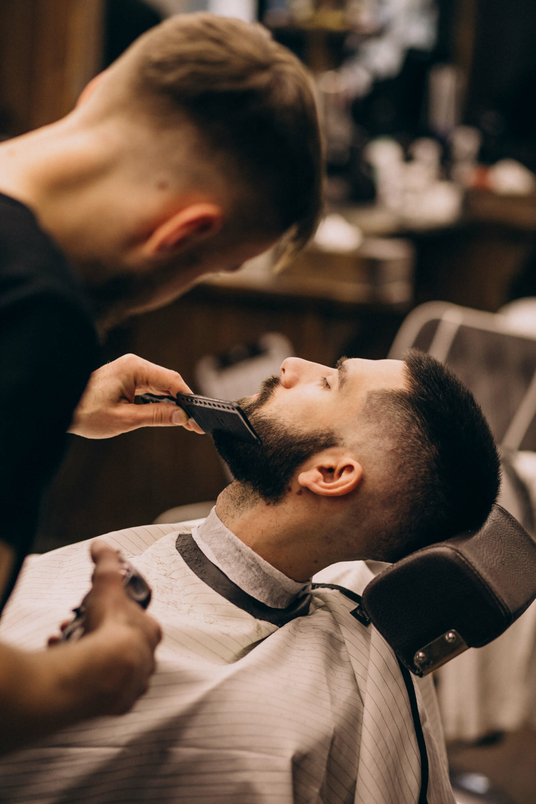 Foto di un barbiere che rasa la barba di un cliente per descrivere la Musica per Barber Shop